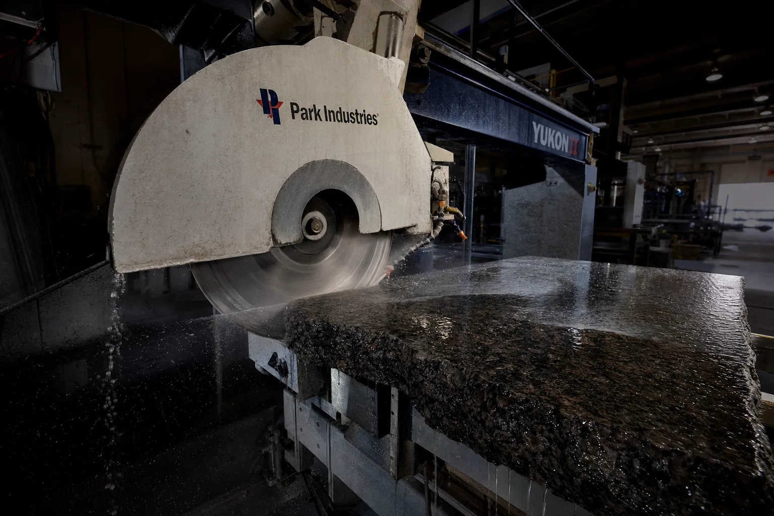 Stone fabrication shop showing a granite slab being precision-cut on CNC equipment